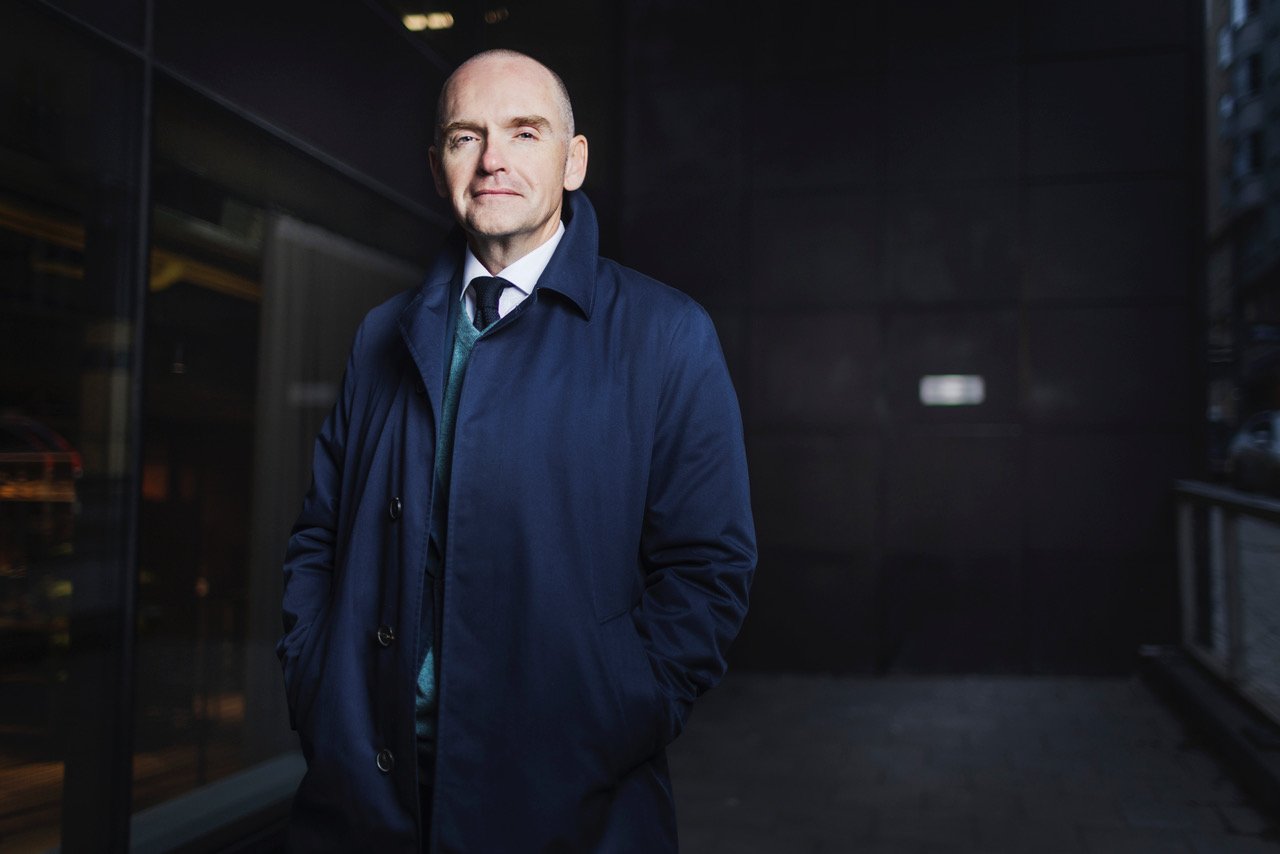 Bob Kitchen standing in a dark passage, wearing a blue coat